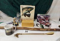 Wide shot showing all lot contents on white surface: brass horsehead shoehorn, fishing book, racing cards tin and box, shaving kit items including soap, brushes, mugs, and a wood handle stick.