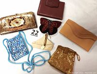 Overview photo showing multiple vintage wallets and change purses including leather, beaded, and mesh designs on white background.