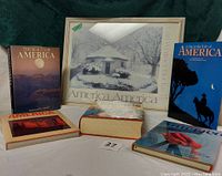 Photo showing the Carl Whitney Bucks print of the Diamond Rock Octagon Schoolhouse with four coffee table books about America arranged in front on a white cloth, highlighting titles and overall condition.