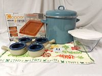 Full view of lot: Farberware soup pot with lid, Copper oven air fryer set in box, Pampered Chef measuring bowl with lid, four ceramic soup bowls, and vegetable patterned kitchen towel.