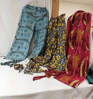 Three pairs of African print cotton pants displayed with tie belts and one with matching scarf