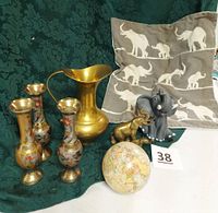 All items displayed together including pillow with elephant designs, brass vases, brass pitcher, elephant figurines, and globe