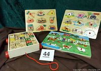 Three wooden puzzles and a wooden wagon with pull string and blocks, arranged on dark fabric