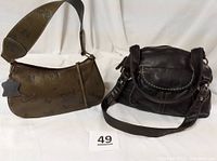 Two purses shown side by side on white cloth: one black genuine leather with multiple pockets and two handle straps, one green leather purse with butterfly embossing and wide strap.