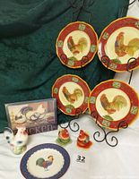 Four red band ceramic rooster plates displayed with a chicken picture, salt and pepper shakers, and a Royal Copley ceramic rooster figurine.