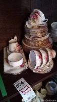 Stack of various china pieces including plates, teacups, sugar bowl, creamer, and tray