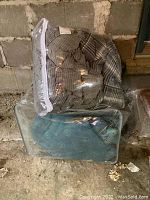 Two comforters in plastic storage bags; twin size with grey plaid pattern on top and teal floral queen comforter below