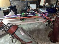 Photo showing white ski boots, multiple pairs of skis, ski poles on a wood topped folding table.