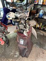 Full view of worn red golf bag filled with multiple golf clubs of mixed brands and types.