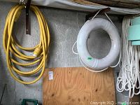 Overview photo showing the marine power cable, white lifesaving buoy ring, and white braided nylon rope hanging against a wall.