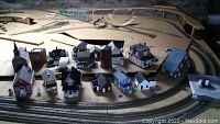 Wide layout view of all 18 HO scale buildings arranged on a wooden platform around model train track