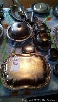 Photo showing an overhead view of various silver plated serving ware pieces including covered dishes, platters, and small serving bowls.