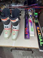 Nordica ski boots and three pairs of skis with bindings and five sets of ski poles on display