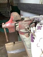 Side view showing jaws and clamp mounting method on the bench vice, red with rust and wear.