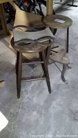 Two vintage stools positioned on a concrete floor in a basement, showing condition and structural details