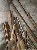 Look at assorted wood pieces stacked in basement corner, showing variety of lengths and sizes including posts and planks.
