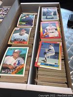 Two boxes filled with assorted baseball sports cards, with visible cards of Don Slaught, Don Schulze, Bob Rogers, Tom Glavine, and John Smoltz among others.