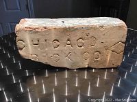 Close-up of the brick showing the 'CHICAGO BRICK CO' stamp and diamond detail on one face.