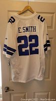 Back view of white Dallas Cowboys jersey with E. Smith and number 22 in blue.