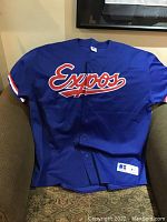 Blue Montreal Expos baseball jersey displayed on chair showing front with logo and brand tag.