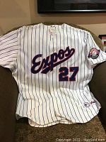 Front and back view of white Montreal Expos baseball jersey with blue pinstripes, showing 'Expos' script and number 27 on back.