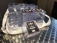 Photo showing multiple sets of clear plastic hockey puck holders stacked, with 13 packs each containing 2 holders for a total of 26 holders.