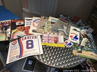 Photo showing an assortment of Montreal Expos baseball programs, posters, photos, patches, and magnet schedules spread out on a table.