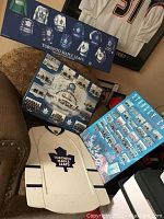 Four Toronto Maple Leafs memorabilia items: two laminated posters on wood, a dry erase board resembling a white jersey, and a laminated blue Stanley Cup champions poster.