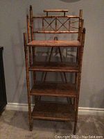 Front view of entire four‐shelf bamboo style shelving unit against wall