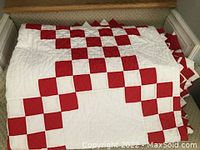 Red and white checkerboard quilt folded on bench