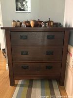 Front view of the wooden dresser showing all three drawers and metal handles.