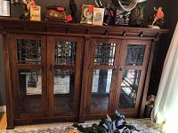 Full-width front view of oak display hutch showing four doors with stained glass panels