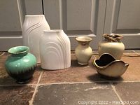 Front view of six Royal Doulton ceramic items including vases and decorative piece, showing color variations and different styles.