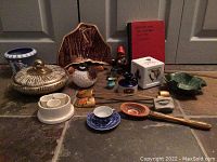 Full view of all miscellaneous decorative items arranged on a stone floor showing various ceramic dishes, figurines, and small decorative pieces