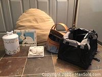 Photo showing all six items in the lot: pet bed, dog food container, travel bag, clock, picnic basket, and decorative plaque.