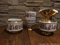 Three Pompei Italy ceramic pieces, two vases and one pot, decorated with classical figures and gold detailing, showing chips and use wear.