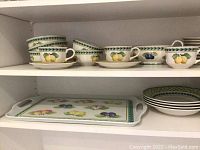 Cups on saucers, small plates and bowls displayed on shelf