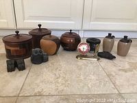 Wide photo showing lot items: wooden containers with lids, two owl figurines, Phinney-Walker clock, black glass inkwell, two beige ceramic jars, black stone decorative piece