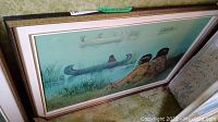 Angled full view of framed painting showing three canoes on water and figures resting at edge.