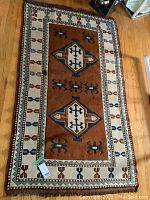 Full view of the rectangular wool rug with geometric and medallion patterns on wooden floor.