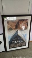Framed Titanic movie poster signed by Leonardo DiCaprio and Kate Winslet, showing the full poster with signatures at the top.