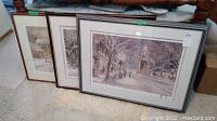 Three framed prints leaning against furniture on carpet