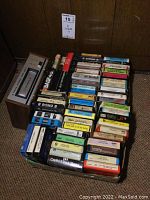 Photo showing a container and box with over 50 assorted 8-track tapes of various labels and colors.
