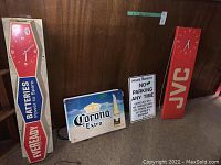 Overview of four wall-mounted signs showing Corona Extra, Private Property No Parking, JVC clock sign, EverReady clock sign