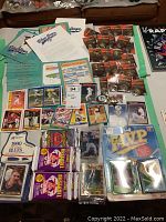 Photo showing a collection of Score baseball cards, early Blue Jays schedules, a few laminated MVP cards, and various unopened sealed packs of baseball cards along with NHL metal pins.