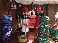 Multiple ceramic beer tap dispensers from Labatts Blue, Alexander Keith's, Molson Canadian, and Molson Export shown on a table with wooden background and other decor.