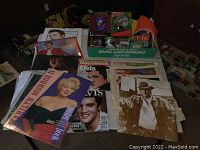 Collection of Marilyn Monroe and Elvis Presley magazines, calendars, and posters including a Marilyn Monroe poster book and Elvis Newsweek magazine.