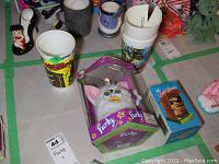 Photo showing boxed Furby electronic toy with clear damage to the box and a separate boxed item with 'The Outfitcase' label visible