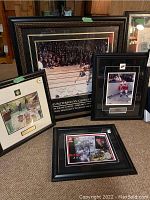 Four framed sports memorabilia items displayed on carpet including boxing/wrestling, hockey, racing, and golf subjects.