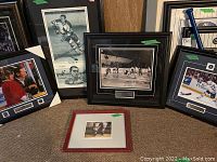 Wide view of five framed hockey memorabilia pieces arranged on floor, some signed, varied frame styles and subjects